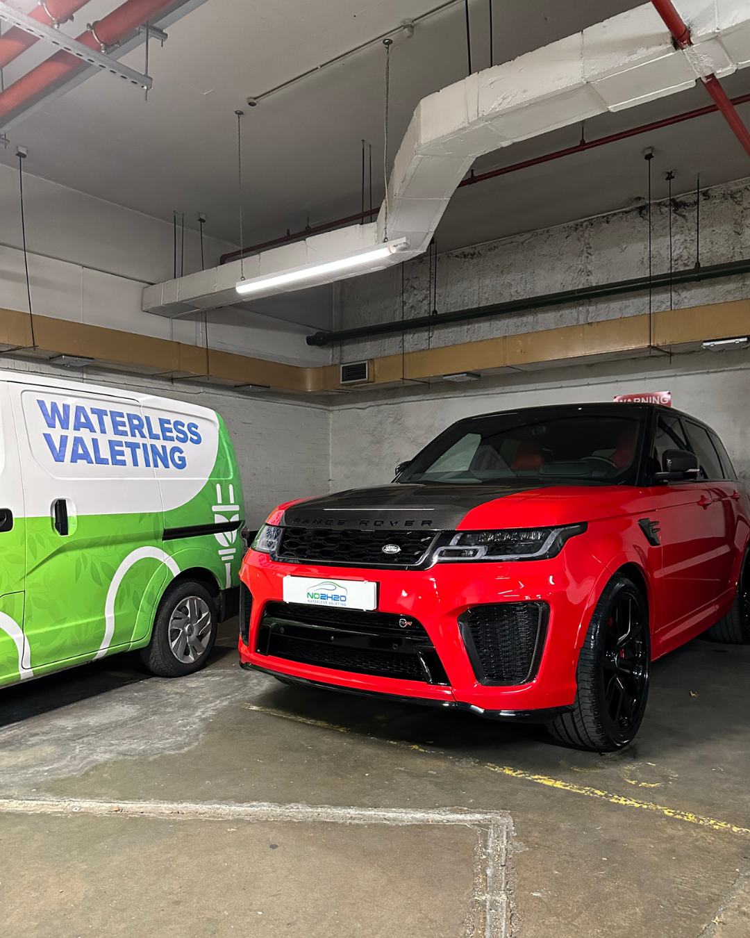 Red Range Rover Sport detailed by NO2H2O next to our branded waterless valeting van in a West London car park